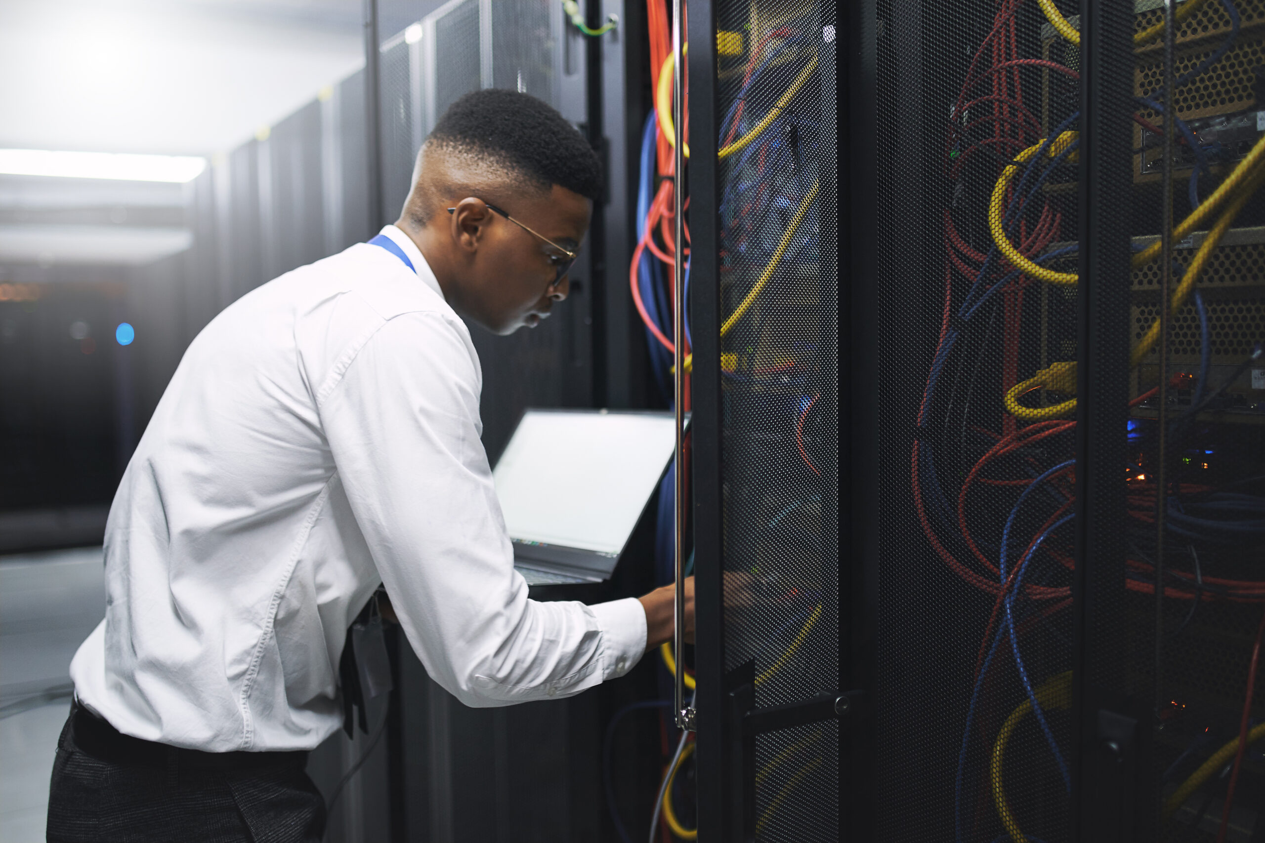 Man, technician and server room with laptop screen for network repair or hardware fault at data center. Male person, IT engineer or computer for technical issue, internet service or system backup.